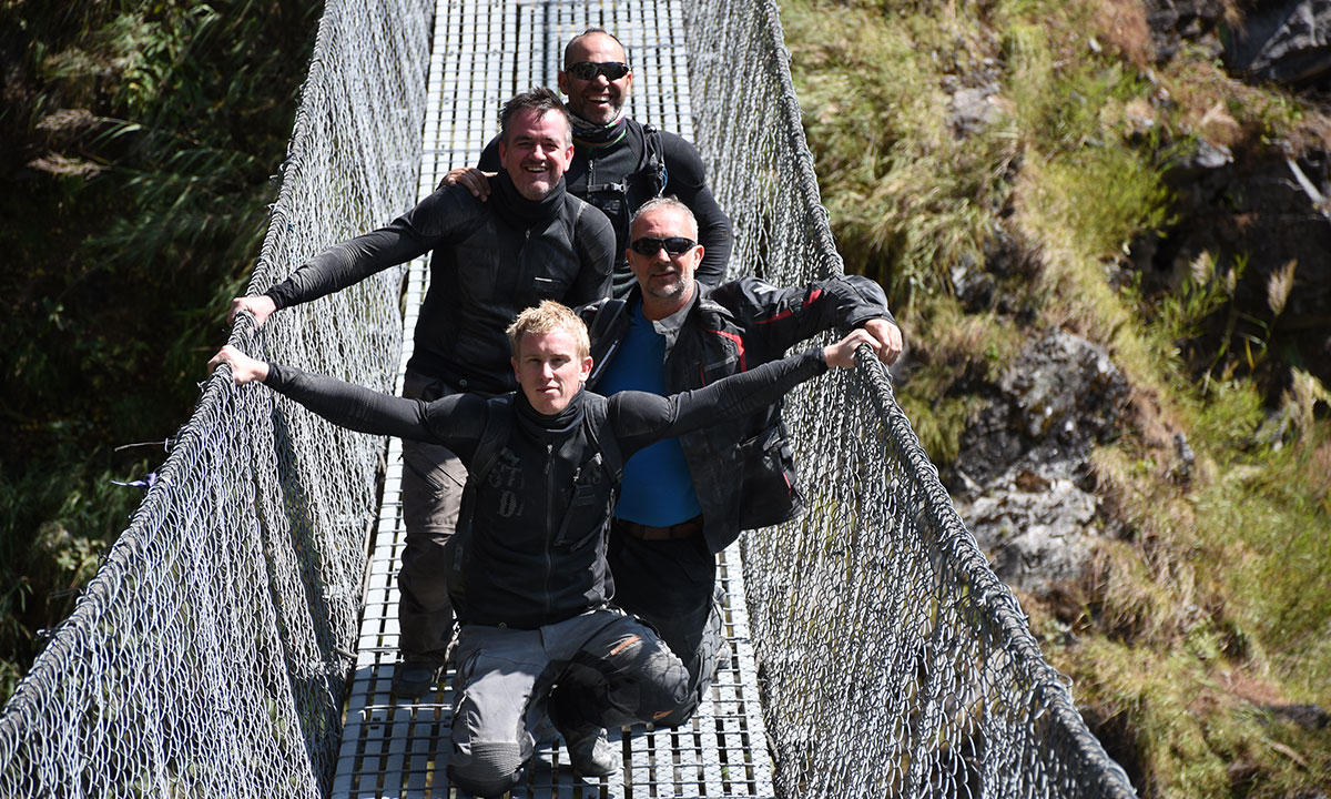 Riders enjoying a break on a suspension bridge.